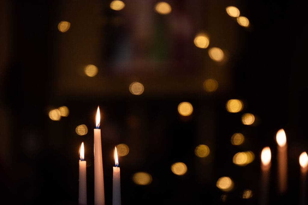 Candles burn as a Christmas tree's lights are reflected in a window. Dozens of worshippers from three congregations attended the candle-lit service on Christmas Eve.