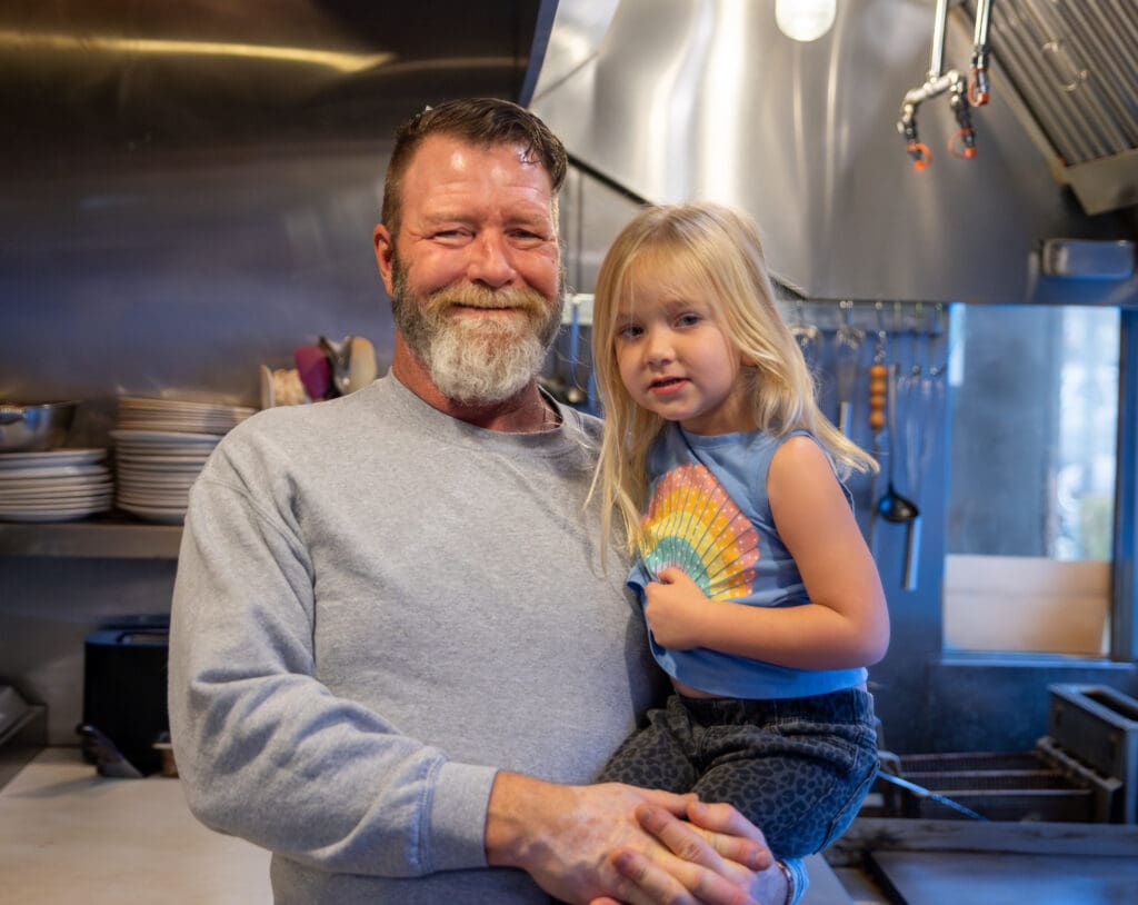 Monte Landucci holds his 3-year-old daughter, Olivia in his arms as he stands in the cafe's open-concept kitchen.
