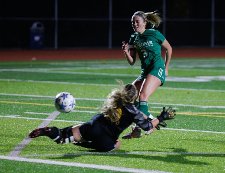 Sehome’s Ava Lontine kicks the ball past Ferndale’s goalie Jaiden O’Neill as she falls to the ground in an attempt to block the ball.