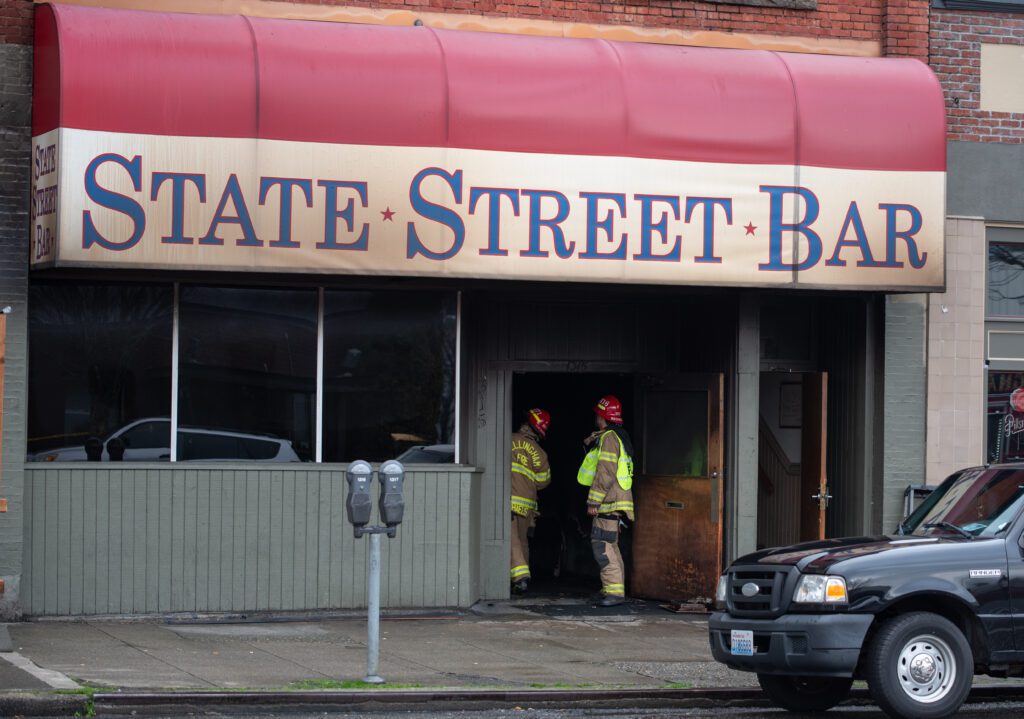 Two firefighters look up inside the State Street Bar.