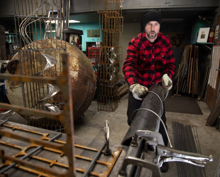 Andy Phillips wraps a metal rod into a spiral in preparation for a fire pit art installation.