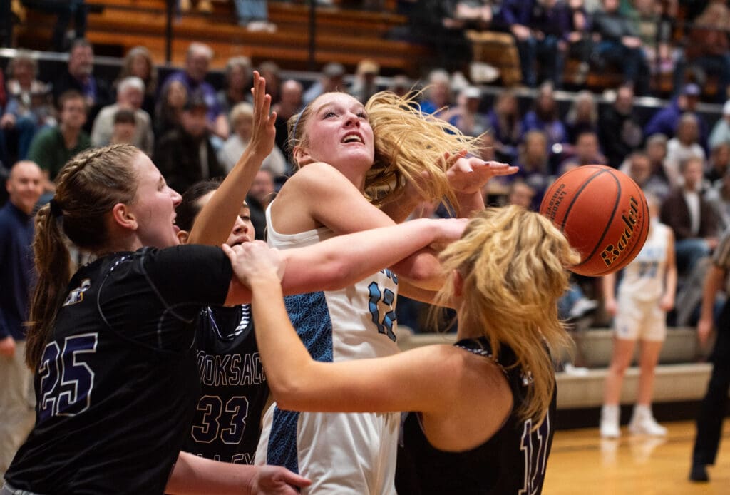 Lynden Christian sophomore guard Ella Fritts looks up to try and make a shot as two defenders wrestle for the ball.