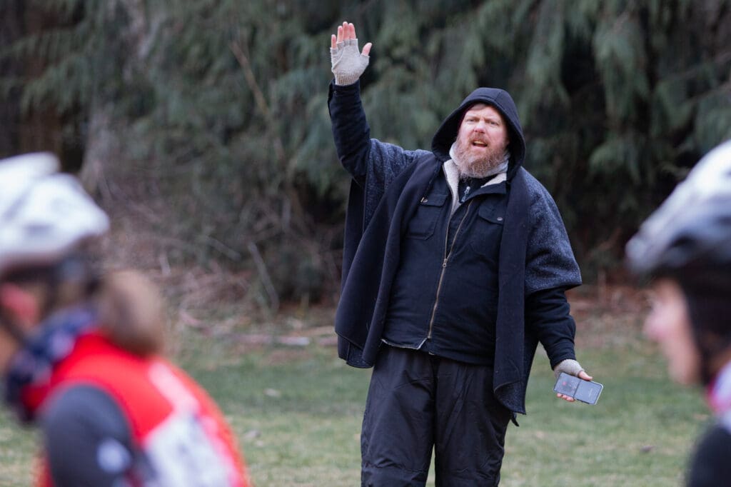 Cascade Cross Director Kip Zwolenski raises his hand as he holds his phone in the other.