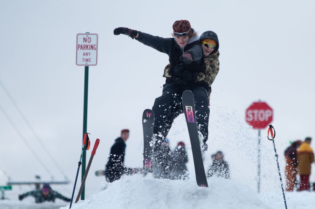 Lucia Stevenson and Jade Gorlach fly together off a snow kicker on Maple Street.