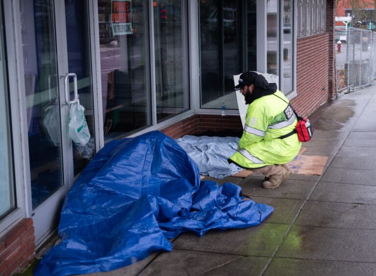 Jeff Enriquez of Risk Solutions Unlimited checks a person sleeping on East Magnolia Street in downtown Bellingham on Wednesday, Jan. 24. Enriquez handed out a granola bar before continuing his patrol.
