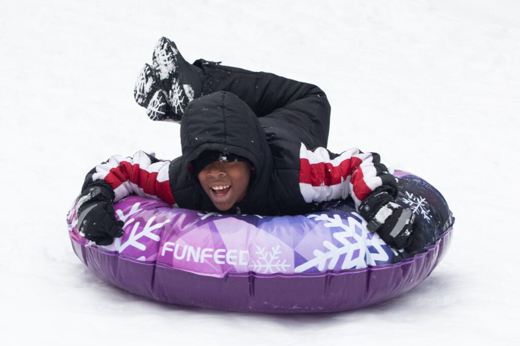 Jayden Bew enjoys a fun slide down the snow slopes on a purple ring tube.