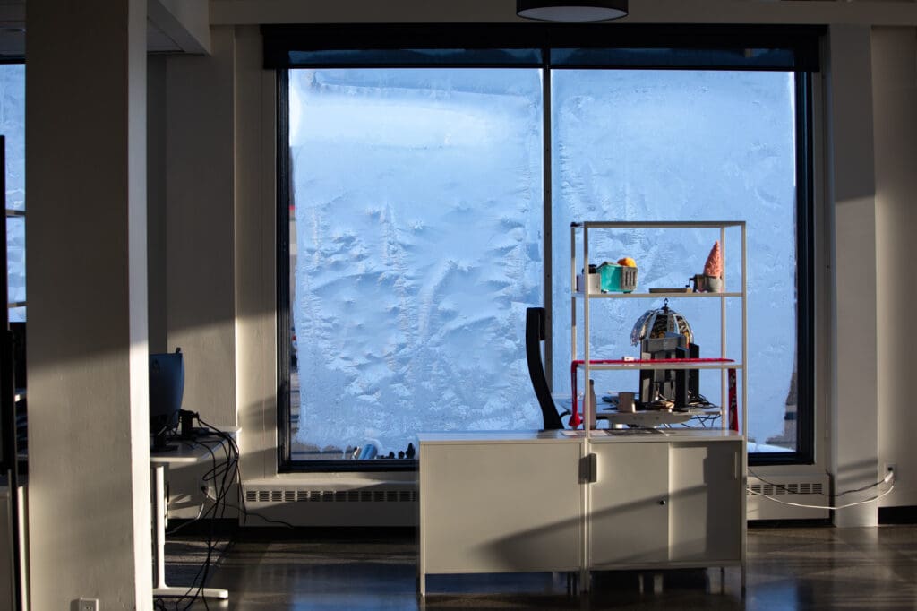 Ice covers the interior window panes of the office for Synergi next to the office tables and chairs.