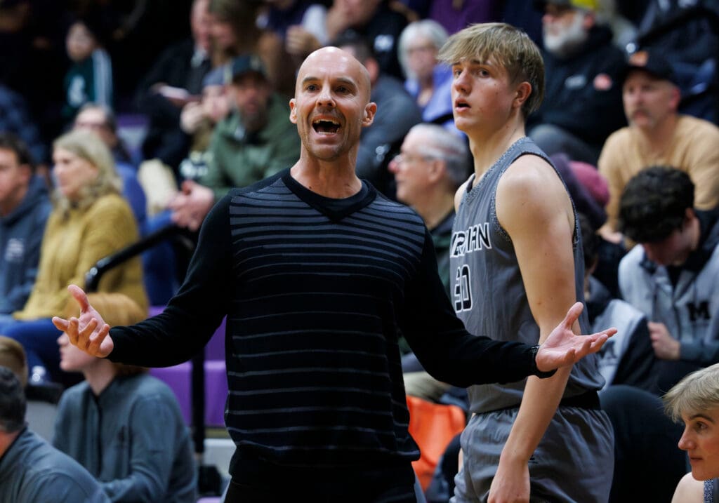 Meridian head coach Shane Stacy argues a charging foul against the Trojans with one of his team members behind him.