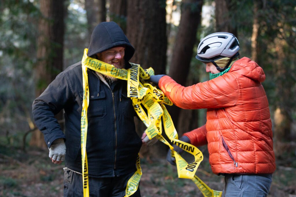 Kip Zwolenski and a Cascade Cross volunteer play around with the yellow caution tape.