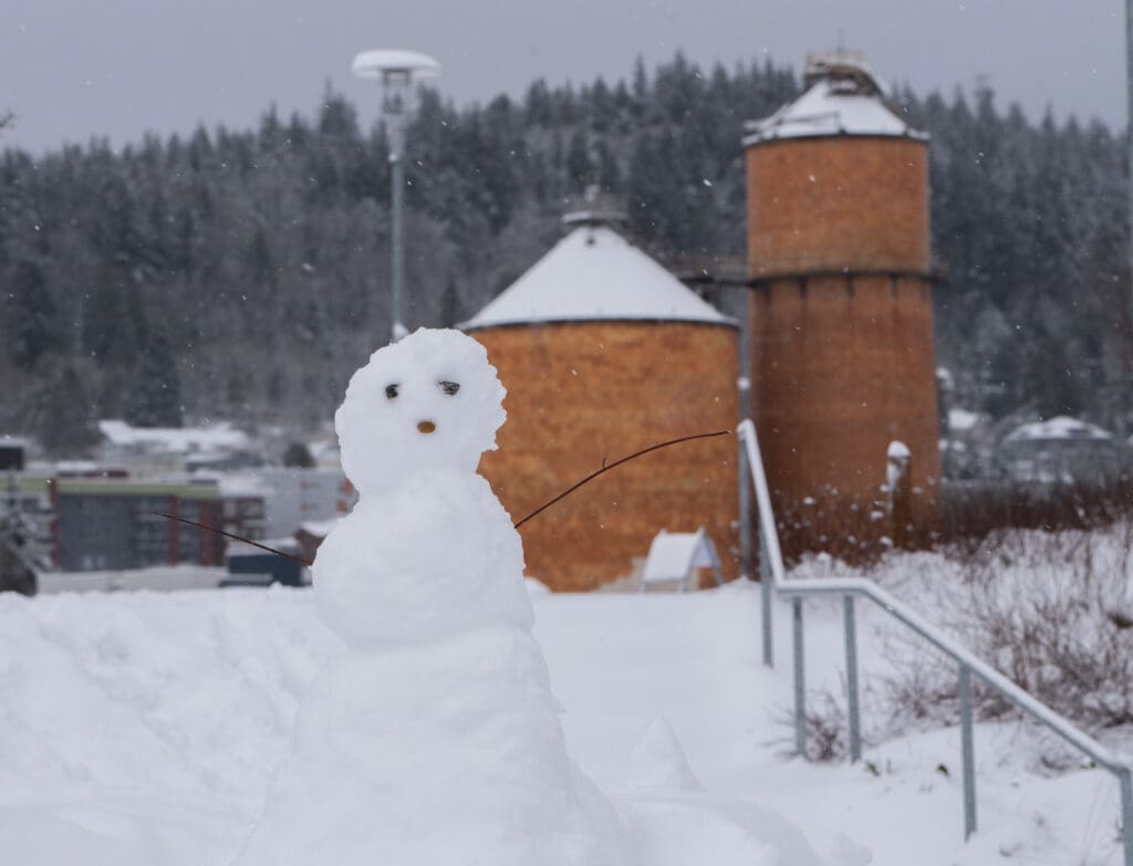A snowman stands at Waypoint Park as silos behind it are covered in snow at the top.