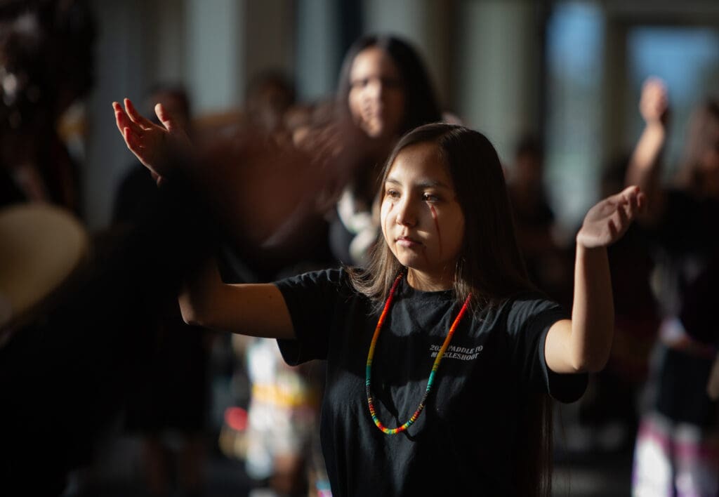 Blackhawk Dancers circle the cafeteria of Sehome High School, one dancer in particular has red face paint streaking down from her eyes and mouth.