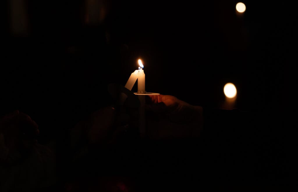 A flame is passed candle to candle as worshippers sing "Silent Night."
