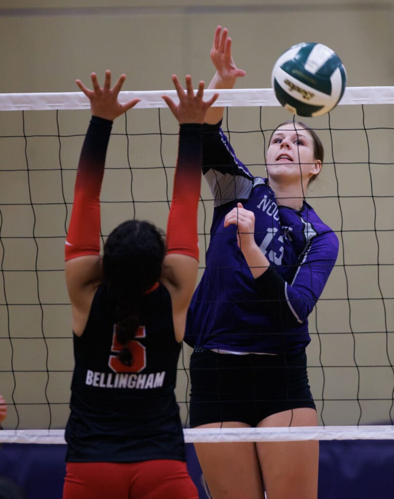 Nooksack Valley’s Grace DeHoog spikes the ball past Bellingham’s Meyesha Riviere as they both leap to take control.