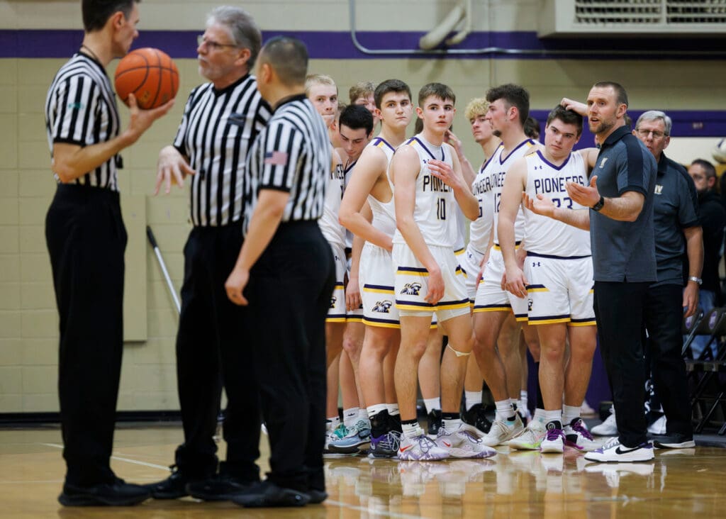 Nooksack Valley head coach Jason Heutink gestures in confusion next to his team as referees discuss a call.