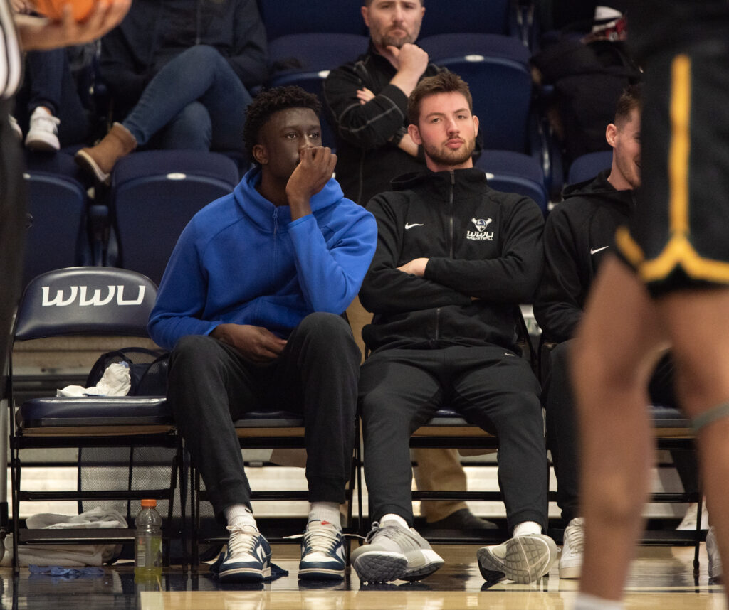 Western sophomore forward BJ Kolly looks on from the bench as other spectators watch from behind and next to him.