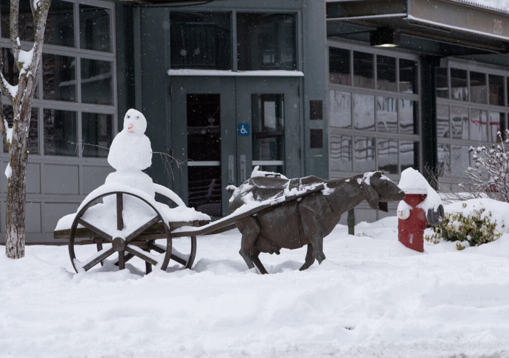 A snowman takes a ride on the back of the "Goat Cart" statue in front of the Depot Market Square.