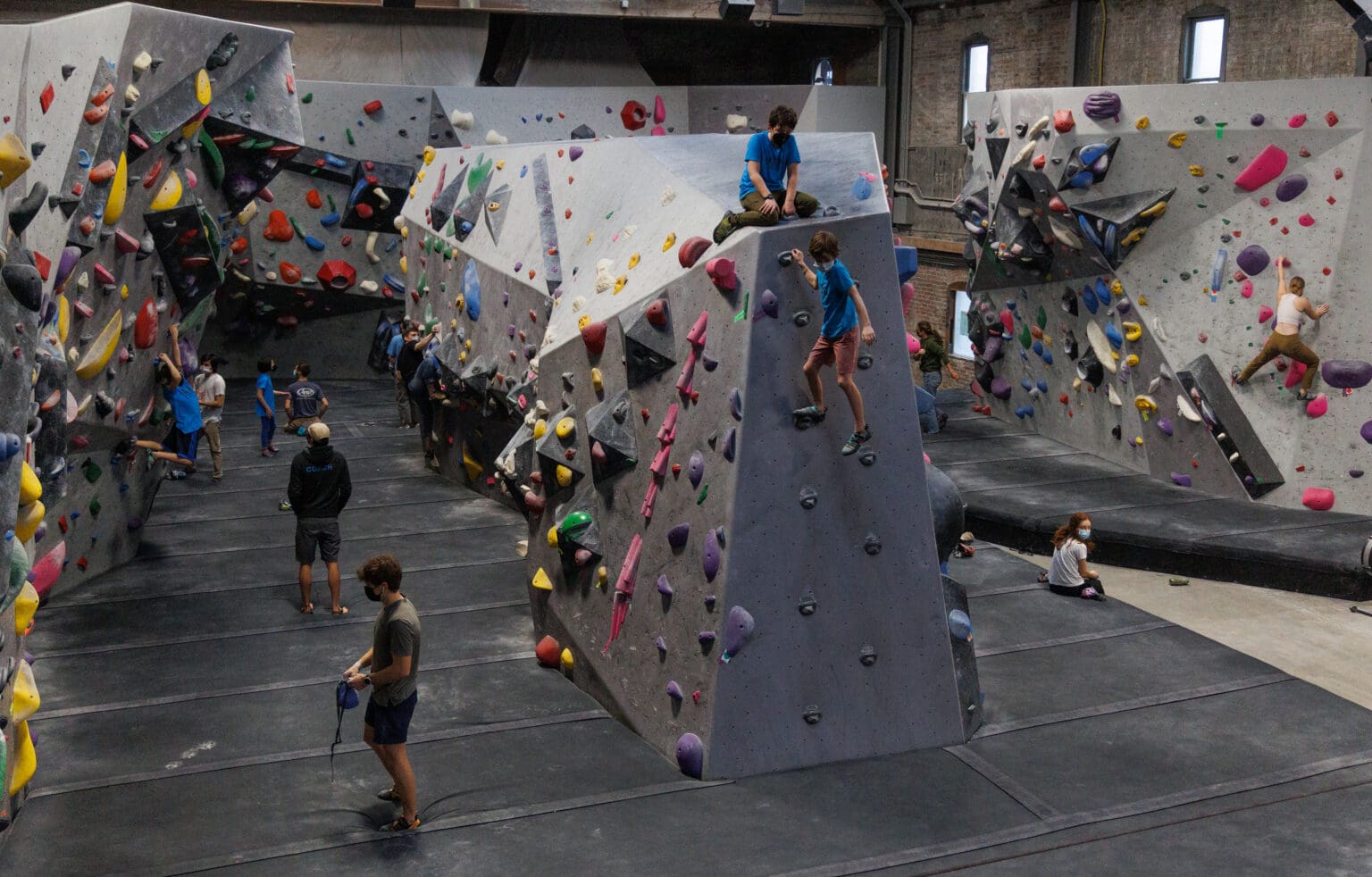 Climbers pick their way through climbing routes on the walls with various colors and shapes for climbers to hold onto.