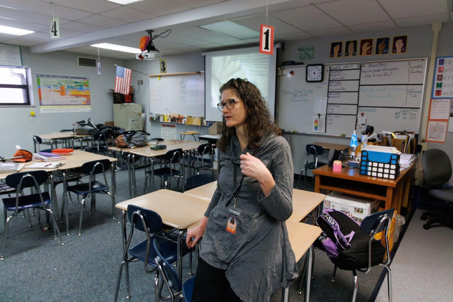 Sixth-grade teacher Julie Creager mimics fanning herself as she describes the school-year heat waves as she sits on one of the many empty student desks in her class.