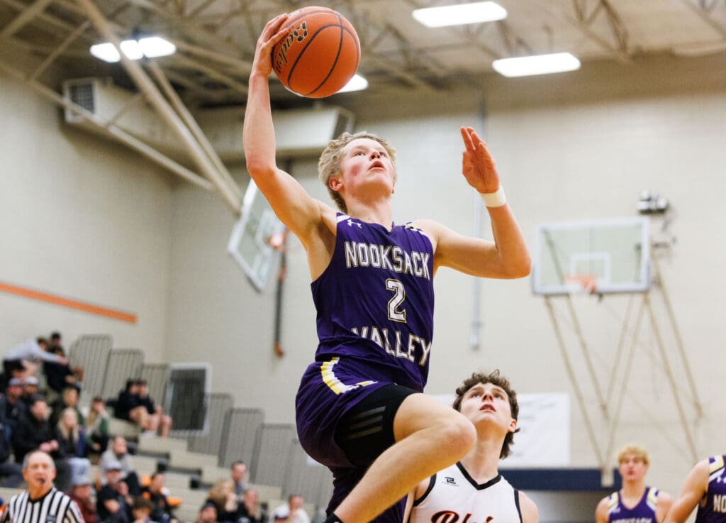 Nooksack Valley's Cole Coppinger leaps and makes a layup over another player.