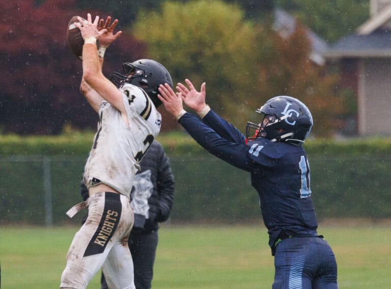 A Royal defender leaps with his arms stretched out to block an intended pass for Lynden Christian's Dawson Bouma.