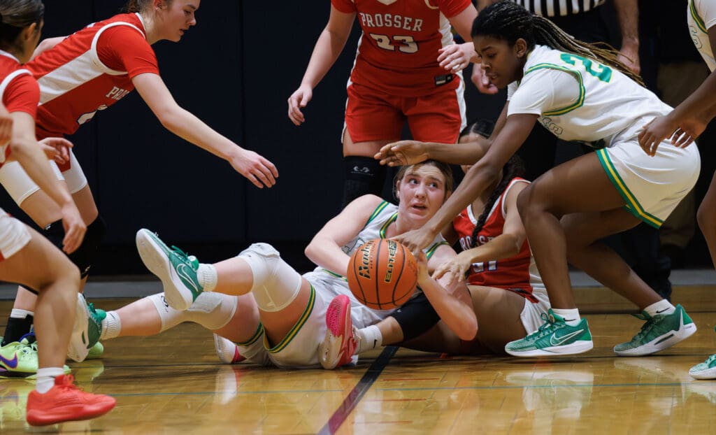 Lynden’s Finley Parcher grabs a loose ball and looks for a pass from the ground as players rush to try to take control of the ball.