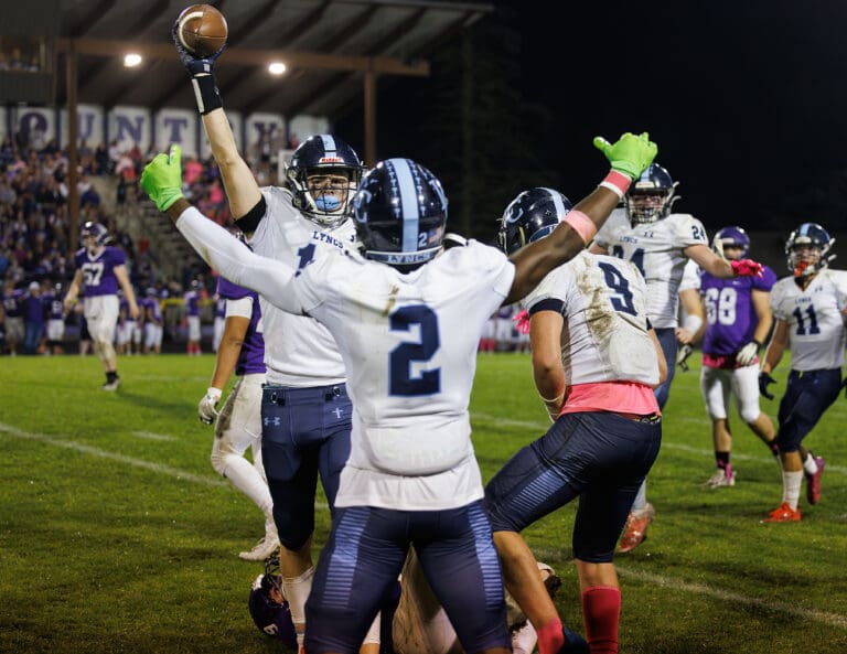 Lynden Christian's Tyson Bajema holds up the ball in celebration as his teammates rush to celebrate with him.