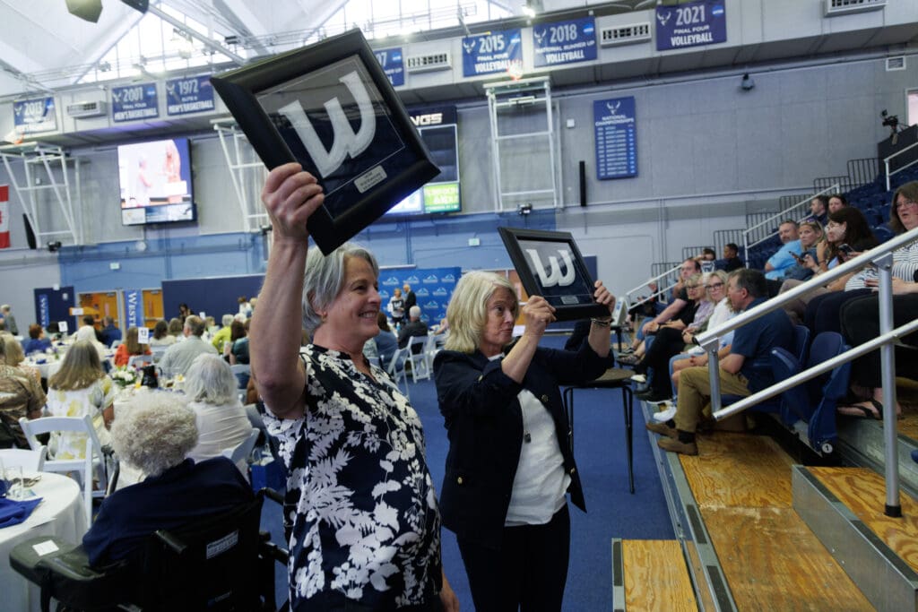 Laura Healy and Joane Larson Ischer stop for a photo and hold up their varsity letters from the school during an awards ceremony at Carver Gymnasium.