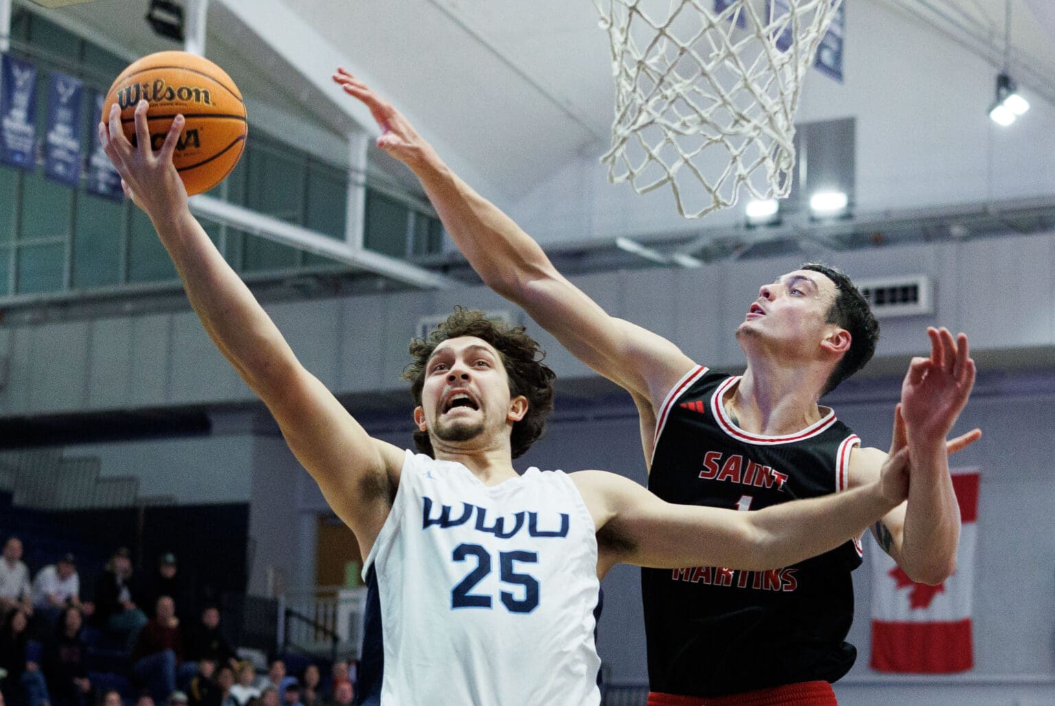 Western Washington University's Louis Grante-Halliday leaps for a layup as a defender tries to reach over him to block the shot.
