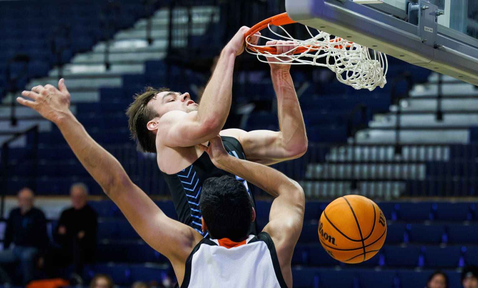 Western Washington University's Liam Clark slam dunks the ball as a defender is left below as he tries to block.