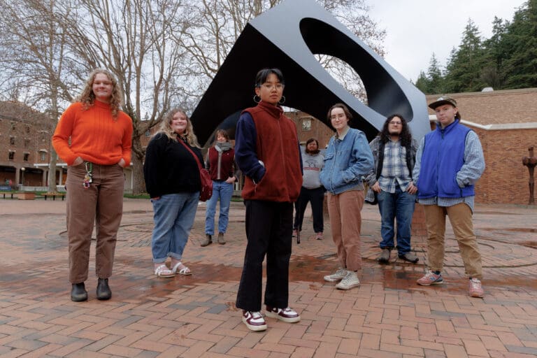 Erin Magarro, center, and other members of Western posing for a group photo in front of an outdoor art piece.