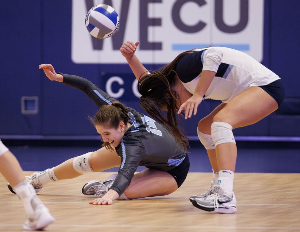 Western Washington University's Abby May and Delaney Speer nearly collide while going for the dig as one of them falls to the ground while the other braces.