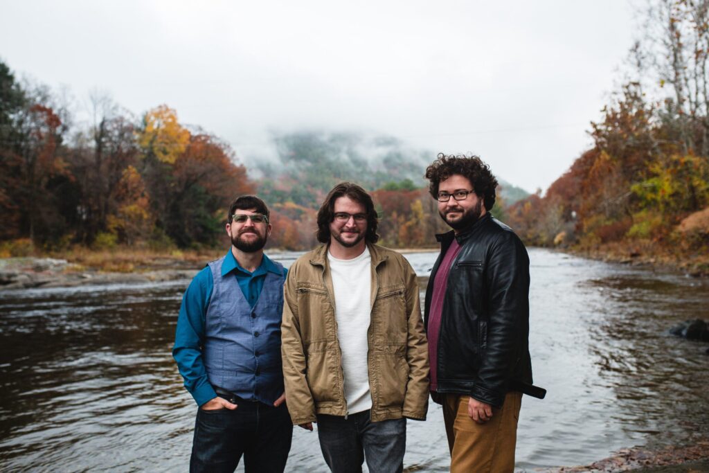 The contra dance/jazz fusion group Faux Paws posing for a photo in front of a river.