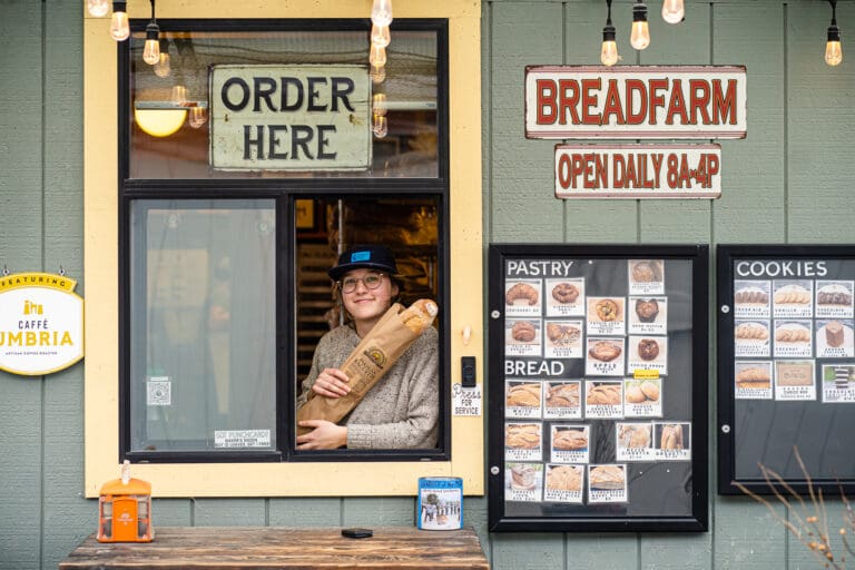 An employee at Breadfarm in Edison holds a Parisian baguette from the drivethru window.