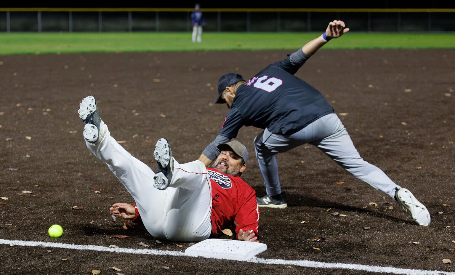 Romer Vivas slides against the dirt with his back to the ground as Jake Ruiz tries to catch the ball.