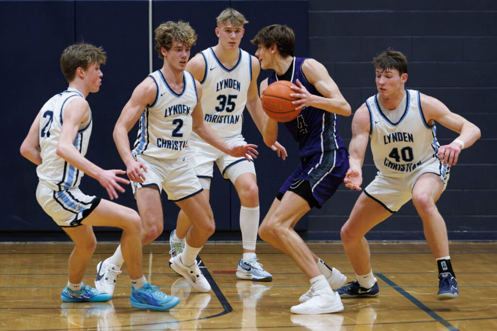 Four Lynden Christian players try to keep Anacortes’ Davis Fogle from scoring by blocking his path with their arms ready to steal the ball.