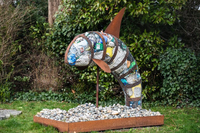 An art piece of a replica of an orca stuffed full of trash.
