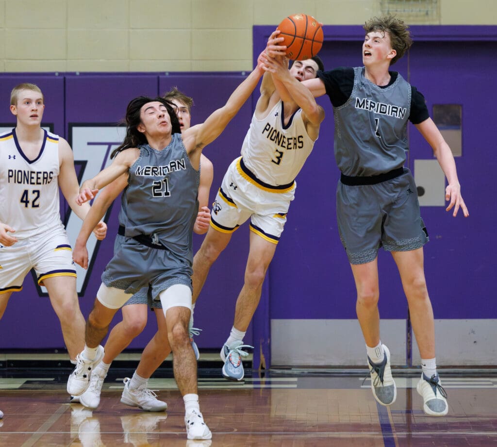 Nooksack Valley's Cory Olney (3) reaches for a loose ball between Meridian’s Taran Burks (1) and Talon Jenkins (21).