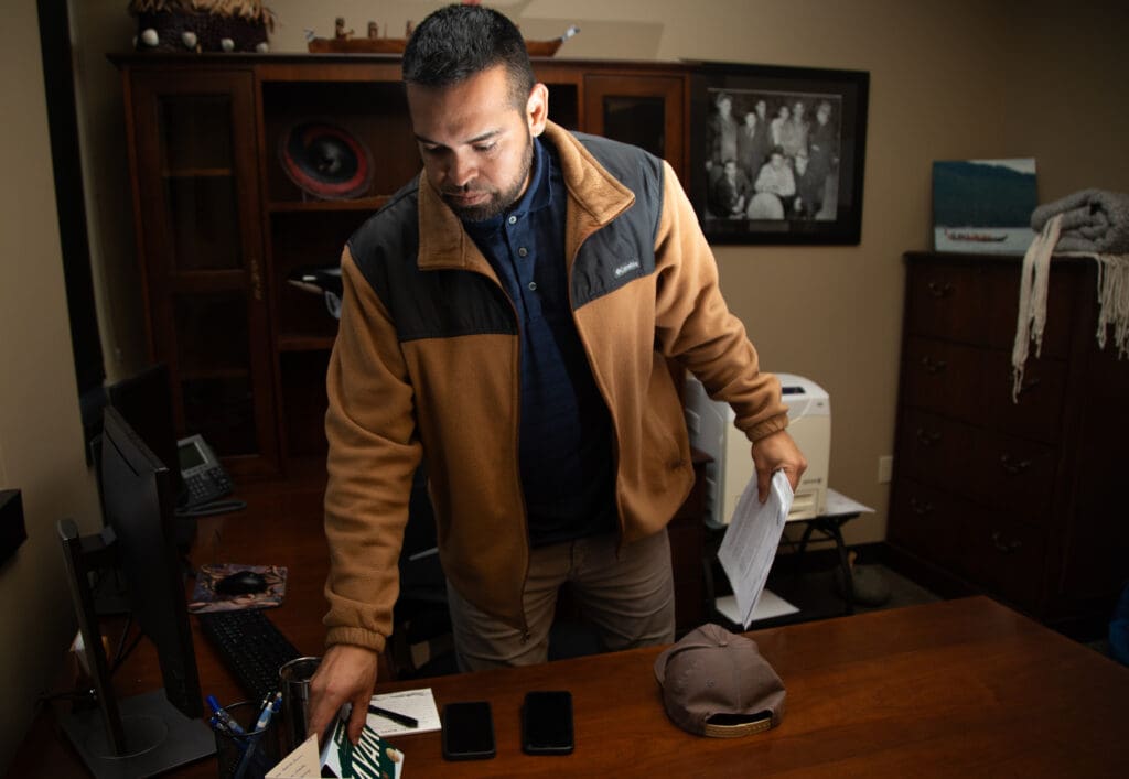 Lummi Chairman Anthony Hillaire prepared to sit at his desk as he clears out items while holding onto a stack of papers.