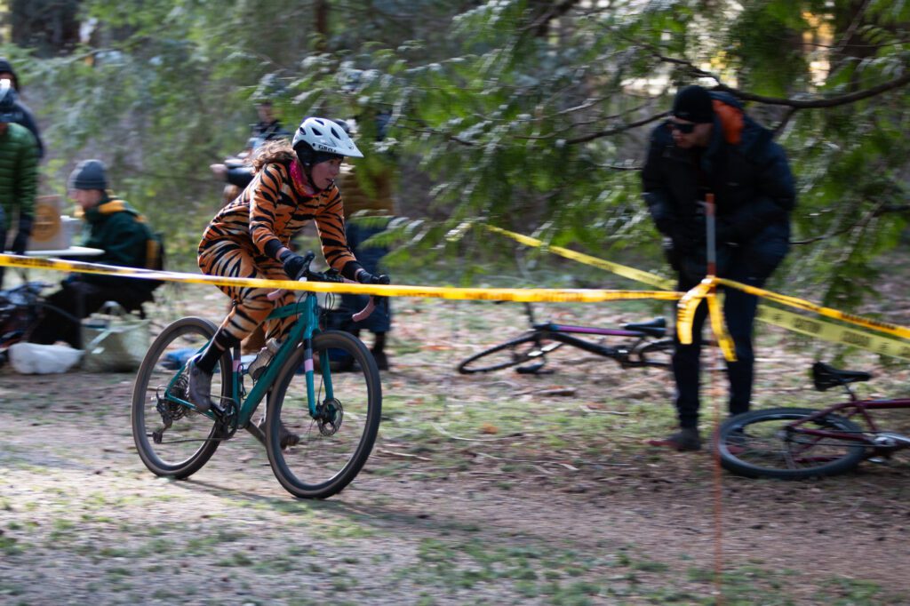 Outdoors columnist Julia Tellman rides her bicycle in a tiger outfit as spepctators watch from behind the yellow tape.