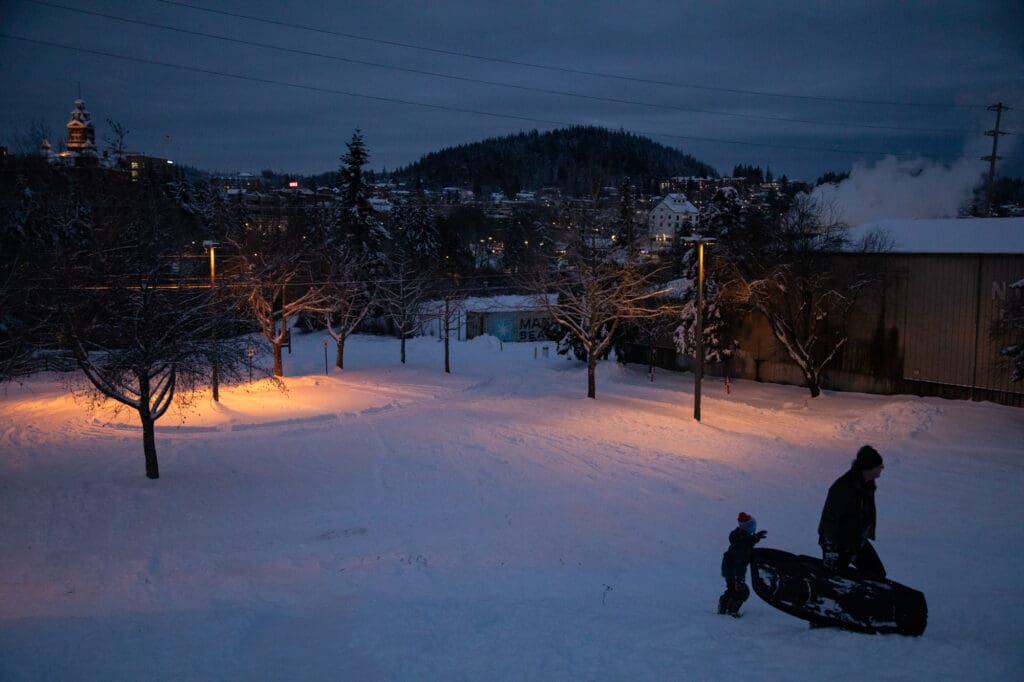 Lucas, 6, left, and Jay Johnson climb the hill lit up by street lamps to sled.