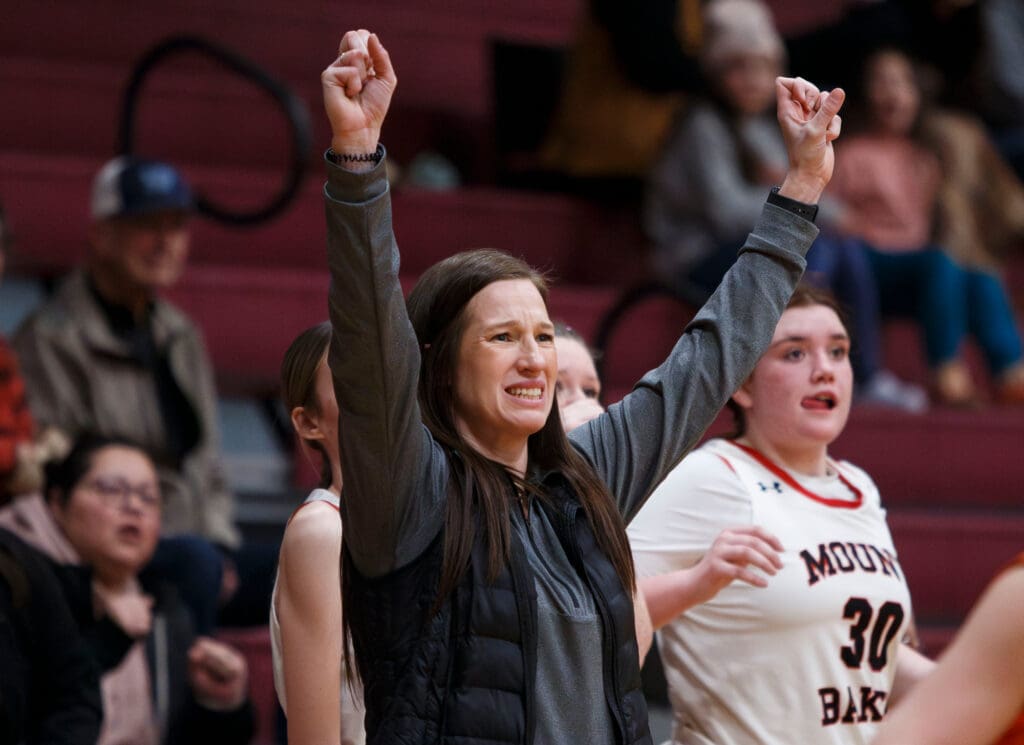 Mount Baker head coach Tiffany Ramirez reacts with her hands up in the air and her teeth clenched as spectators watch from beside and behind her
