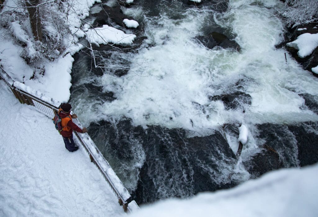 Travis Wheeler looks over a snowy Whatcom Creek as the water rushes right below him.