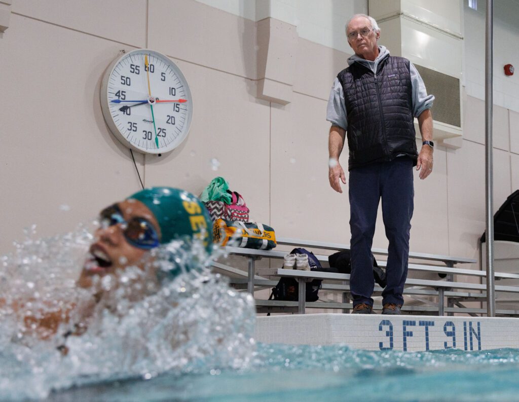 Sehome swim coach Don Helling watches over swimmers from the sideline.