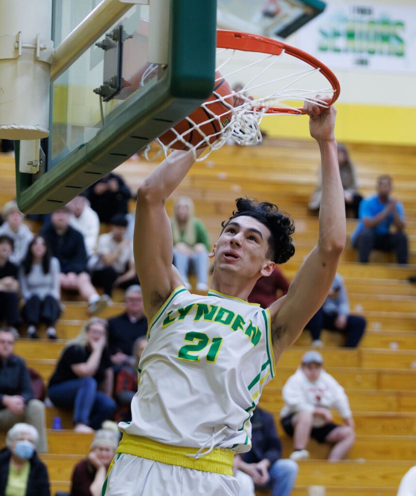 Lynden’s Anthony Canales dunks the ball as spectators watch from the wooden bleachers behind him.