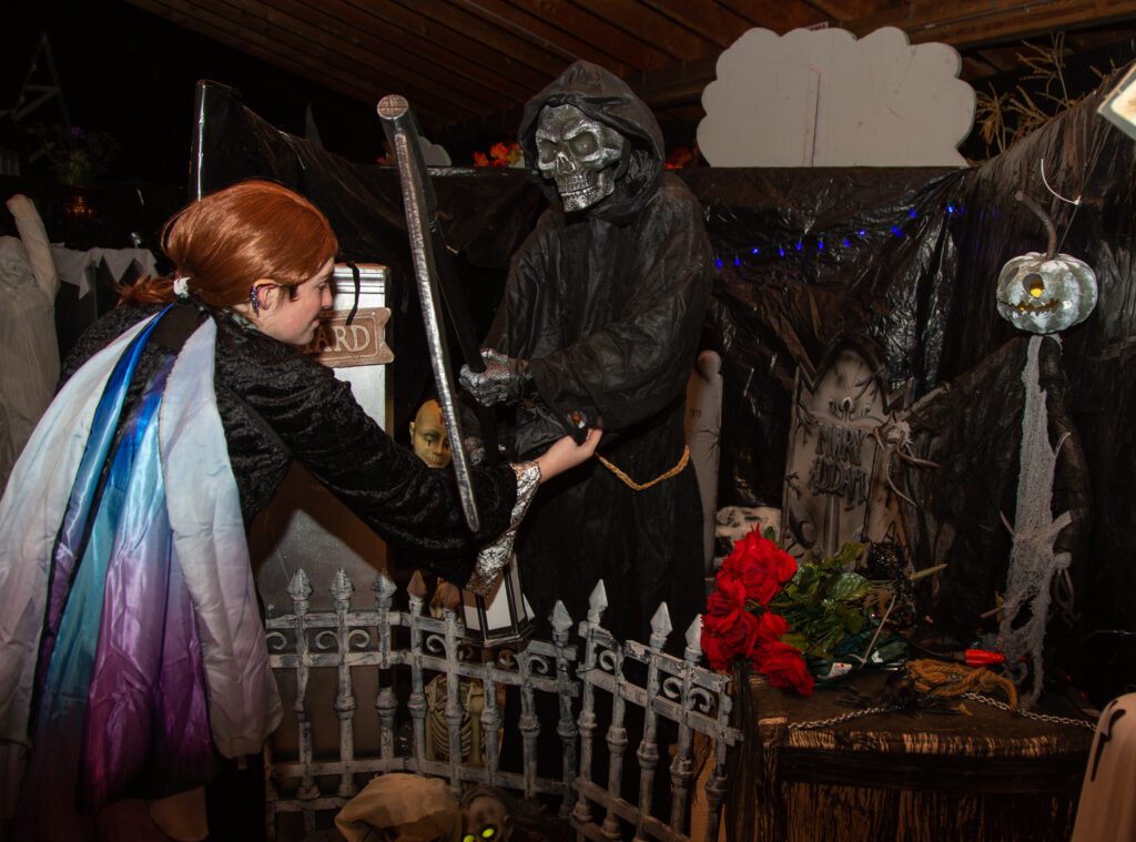 A costumed volunteer adjusts a grim reaper installment.