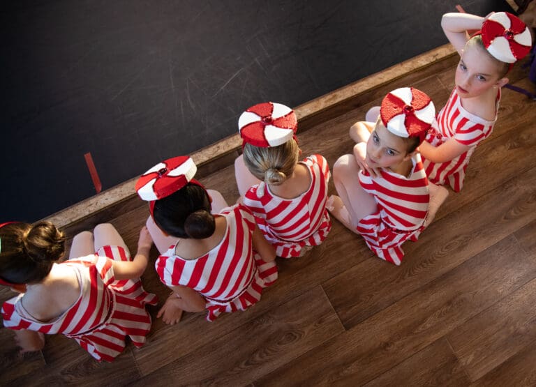 A group of young dancers line up while wearing peppermint-themed hats and outfits.