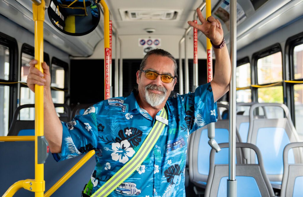 Jeff James posing with a peace sign in the walkway of the bus.