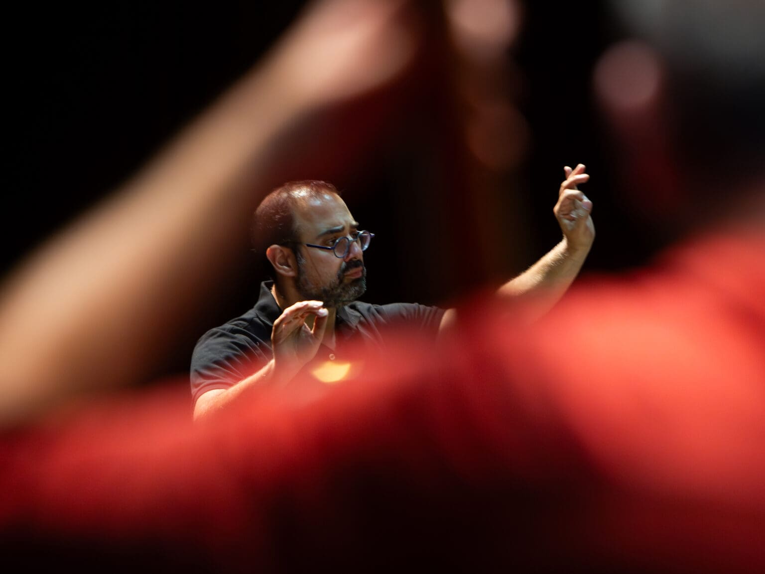 Yaniv Attar conducts a rehearsal of the Bellingham Symphony Orchestra with both his hands in the air.