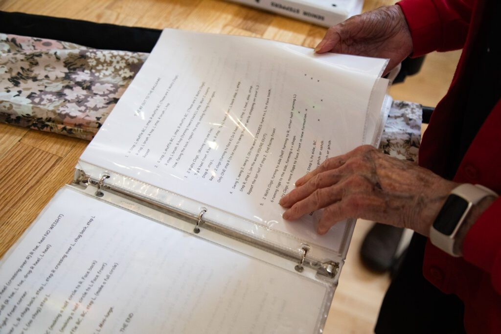 Elmerine Strickland flips through a binder of numbered tap dance routines she choreographed.