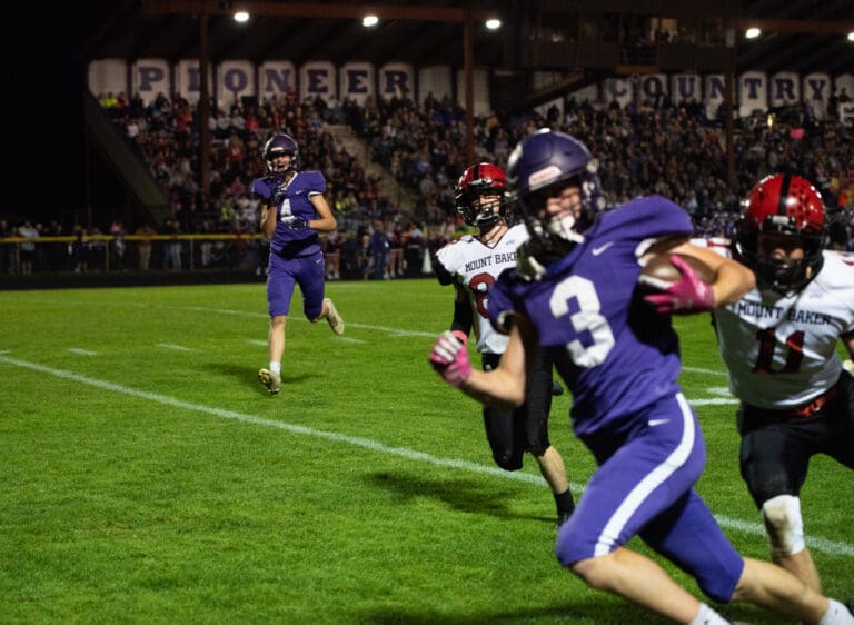 Nooksack Valley junior wide receiver Cole Bauman (4) yells in celebration as he watches his teammate run with the football away from two defenders.